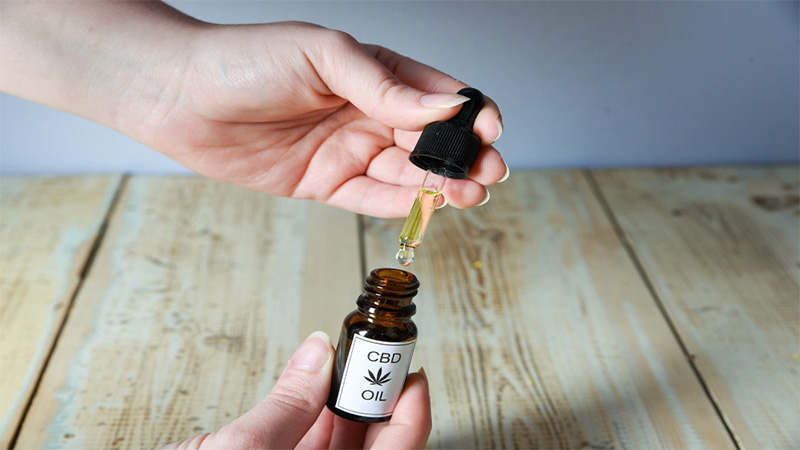 A woman taking CBD oil from the bottle using a dropper