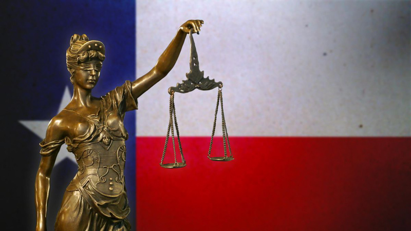 Goddess of justice statue with Texas flag in background