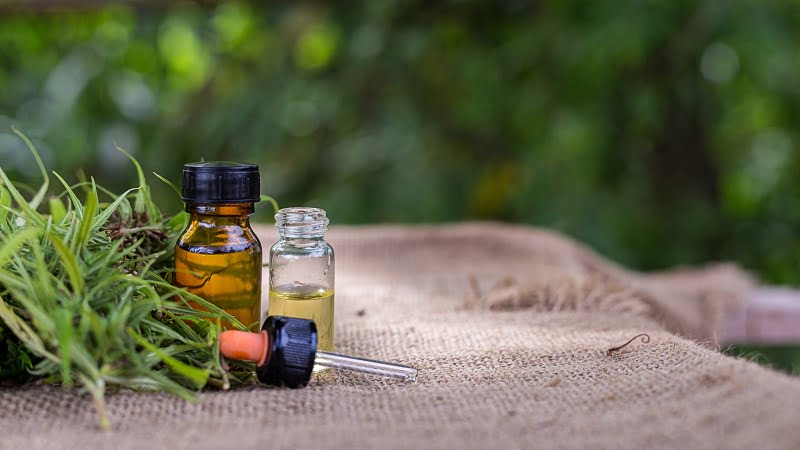 Medicinal CBD oil extracts in bottles with a dropper and hemp leaves on a mat