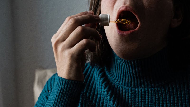 woman taking a CBD oil using a dropper