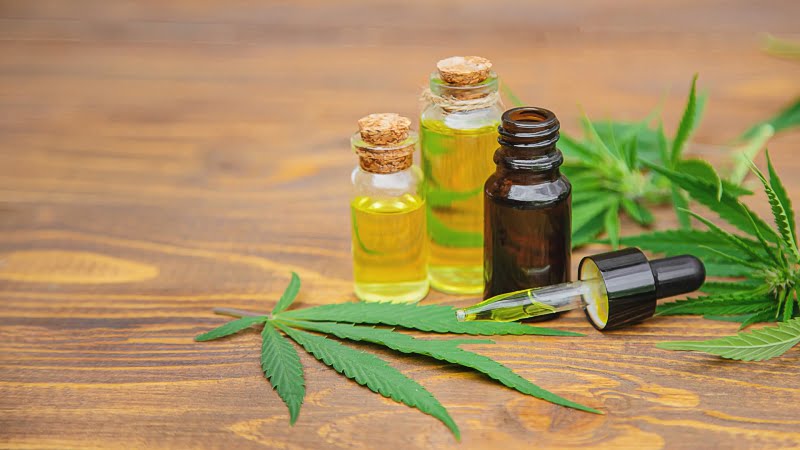 CBD oil extracts in bottles with a dropper and cannabis leaves 