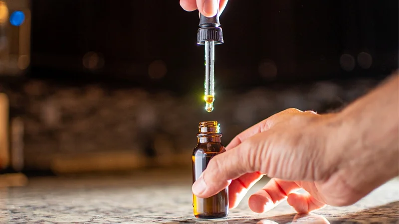 a hand taking a CBD oil with a dropper