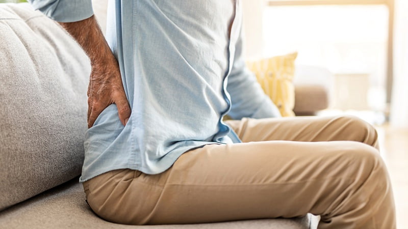 a man having lower back pain while sitting on a couch