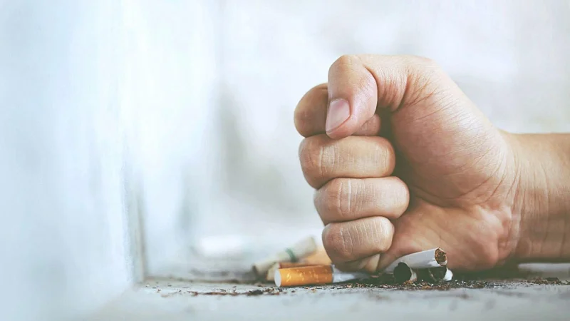 man hand smashing cigarettes on a concrete floor
