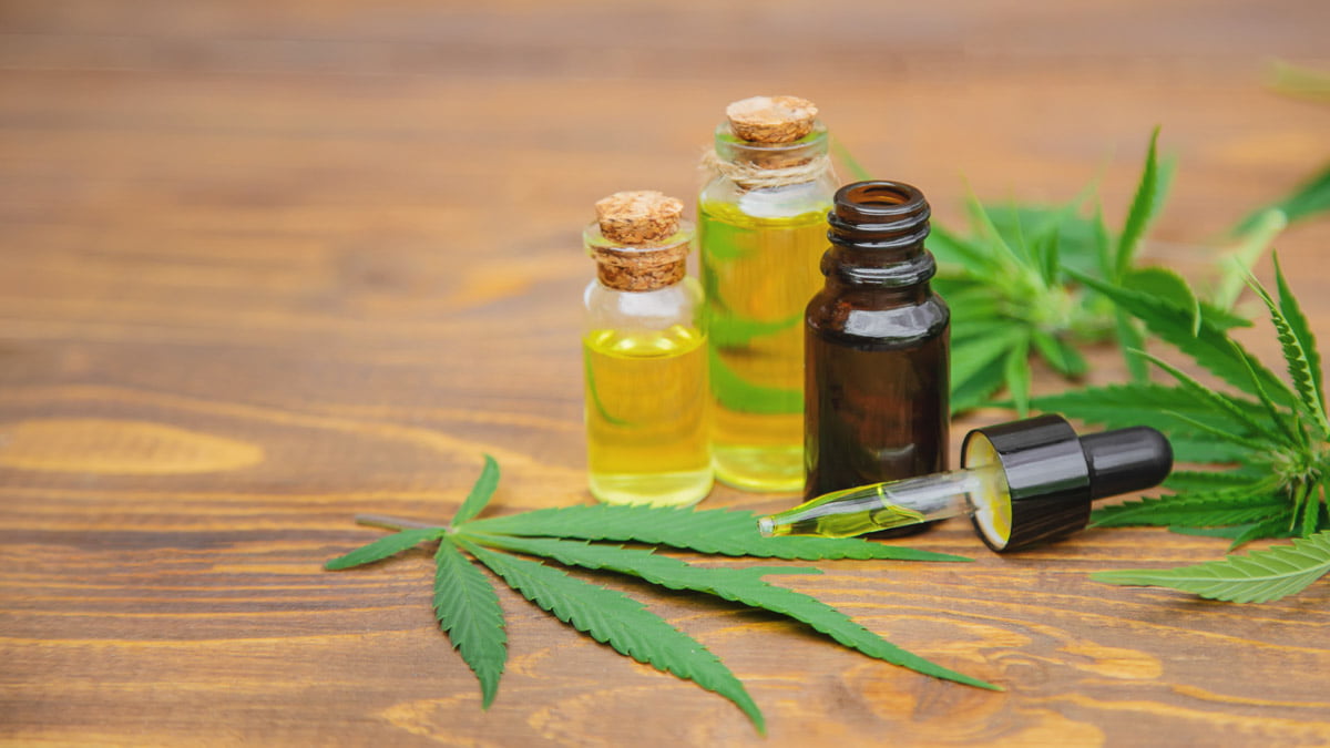 CBD Oil with Hemp Leaves in Wooden Surface