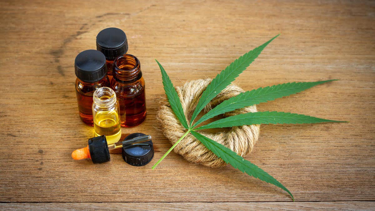 CBD Oil Bottles with Hemp Leaf and Rope on the Wooden Surface