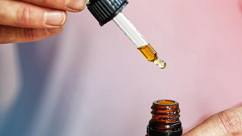 woman taking CBD oil using a dropper