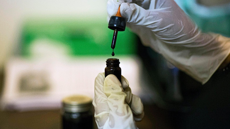 hand with gloves taking CBD extract using a dropper 