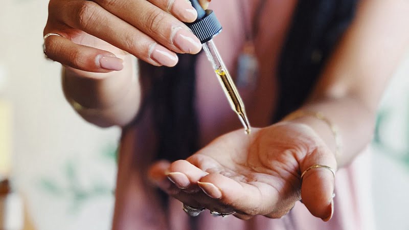 Woman putting CBD oil on hand using a dropper