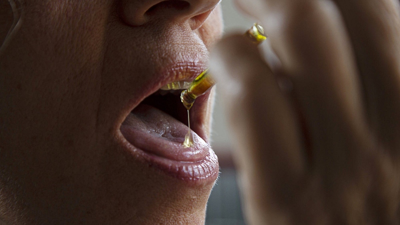 A woman taking CBD oil orally using a dropper