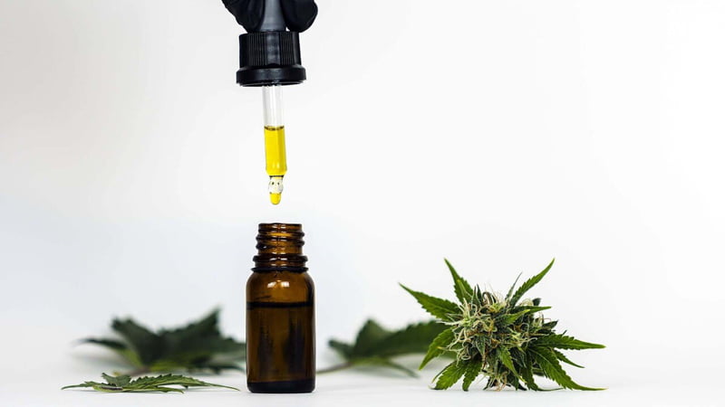 CBD Oil for Cancer with Hemp Leaves on the White Surface