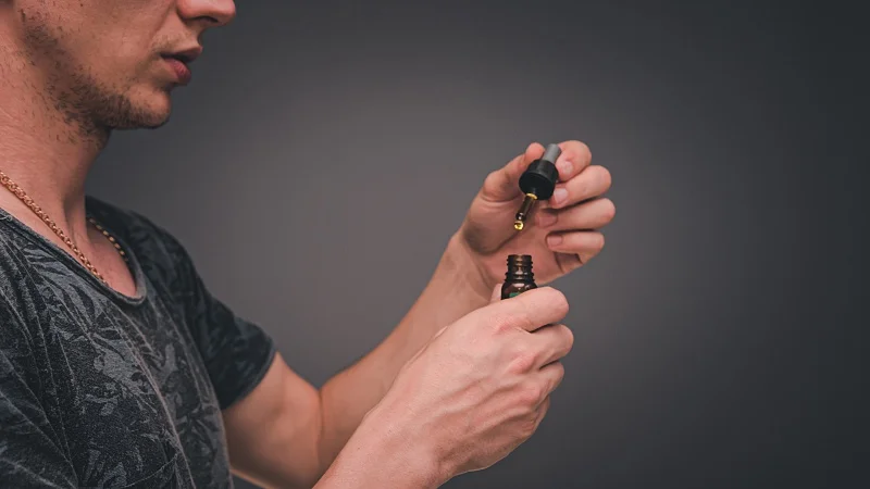 a man taking delta 8 thc oil from a bottle using a dropper