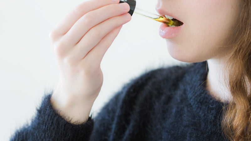 Woman Wearing Black Taking CBD Oil