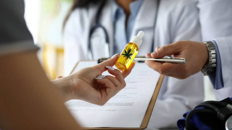 Patient Holding CBD Oil in Front of Doctor