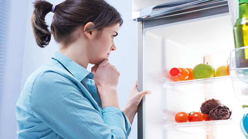Woman Thinking to Put CBD Oil Inside Refrigerator