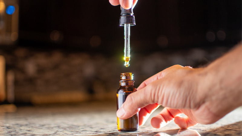 Hand Holding CBD Oil Bottle and Dropper