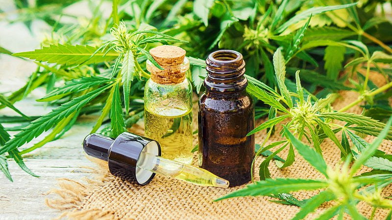 CBD oil and tincture in bottles, a dropper, and hemp leaves