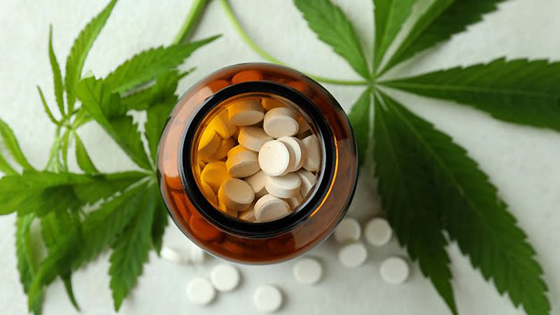 top view image of a bottle with tablets and hemp leaves on a white texture background