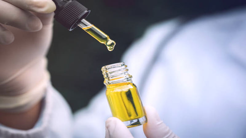 Researcher with a dropper and CBD oil bottle