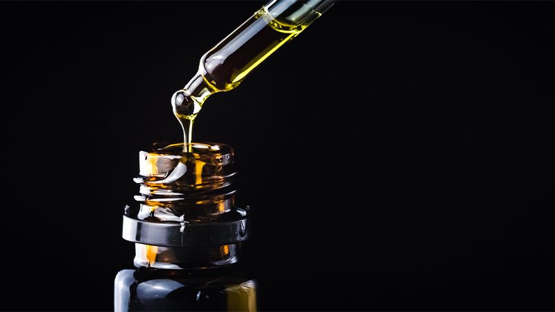 Close up of CBD oil showing the oil in bottle and the dropper