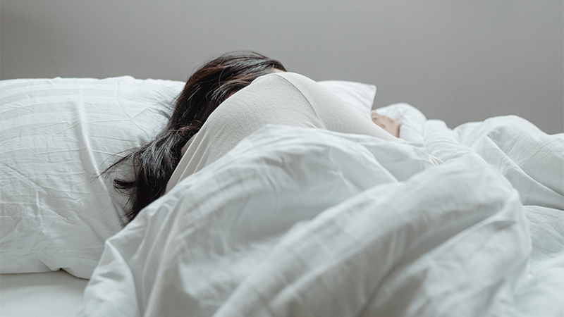 Image of woman sleeping under the blanket on bed