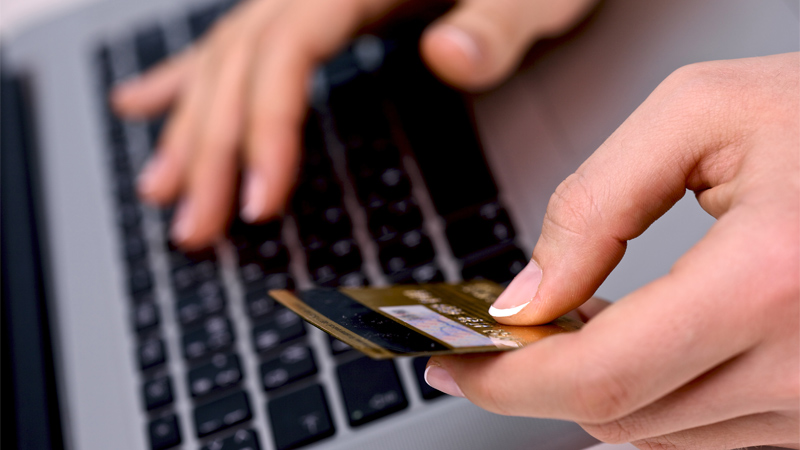 Person using a laptop holding a credit card