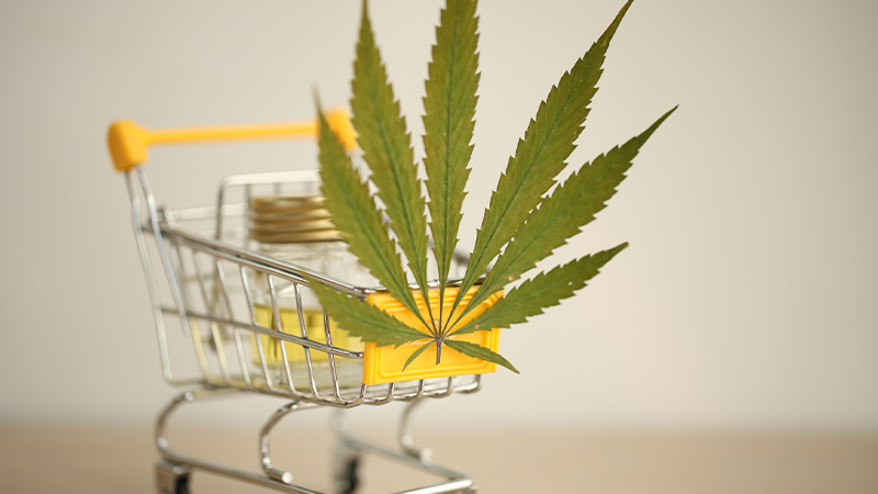 A bottle of CBD oil with hemp leaves on a shopping cart