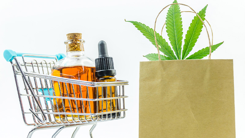 Cart with CBD oil bottles and a shopping bag on the right side with hemp leaves showing