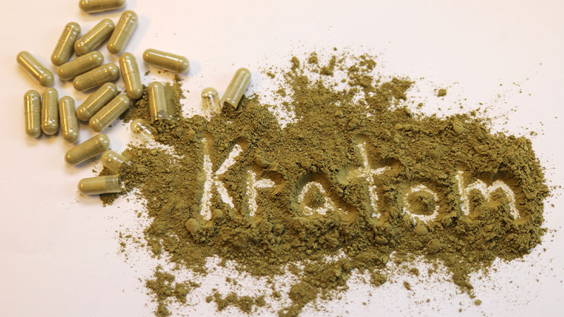 Kratom capsules and powder scattered on the table