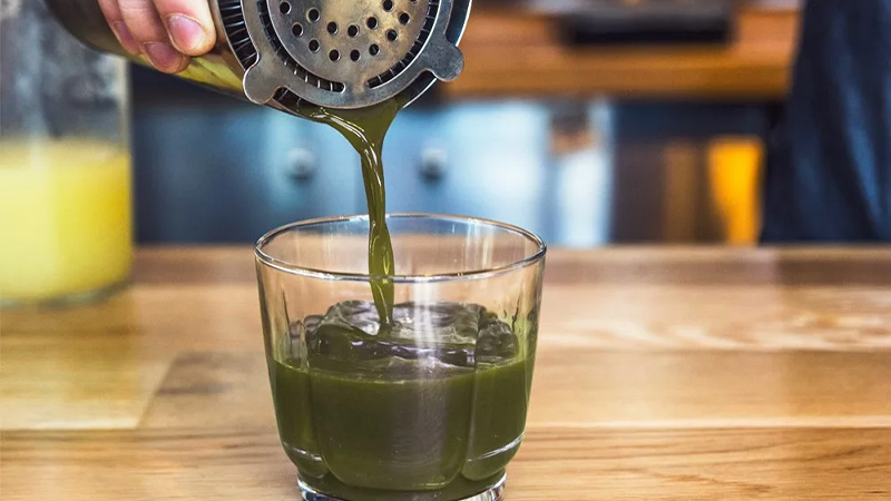 A bartender pouring Kratom drink in a small glass