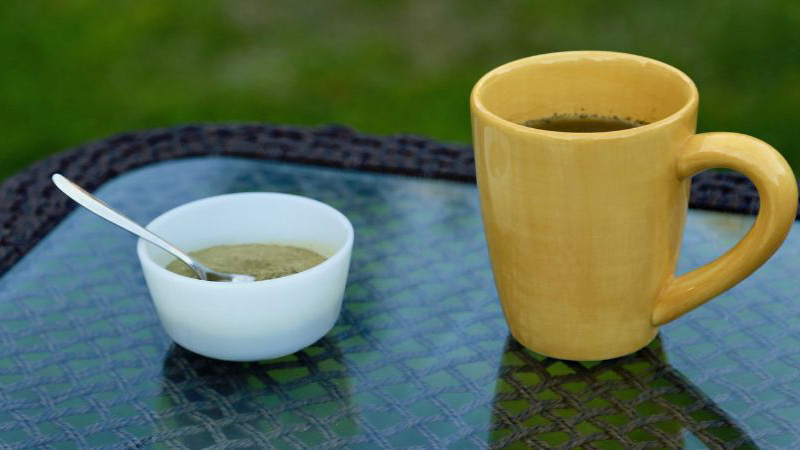 Kratom dried and powdered leaf on a mini bowl and Kratom tea on a table