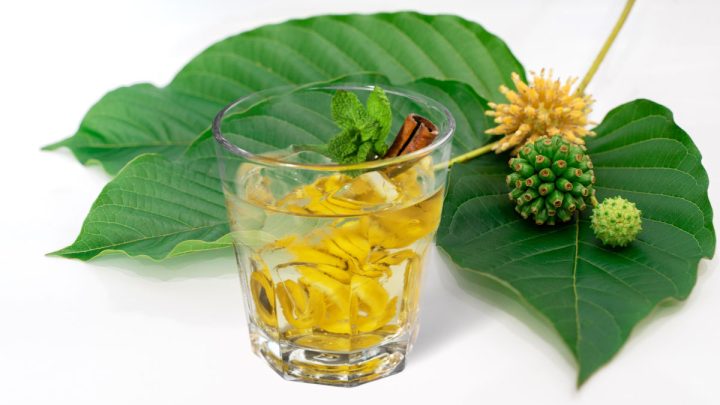 Alcohol beverage in a glass with kratom leaves on the back
