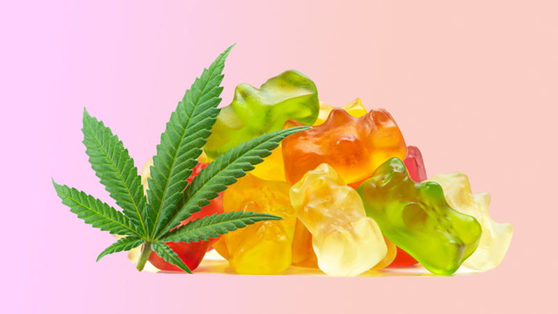 Assorted Delta-8 gummies are piled next to a cannabis leaf.