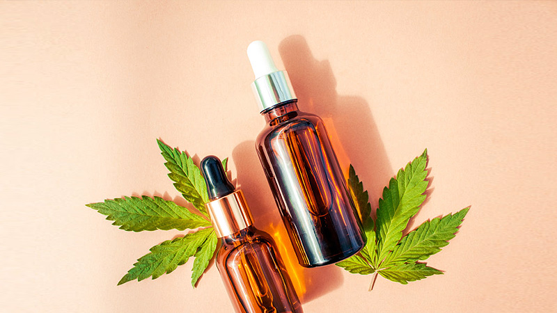 Delta 8 tincture bottles with different volumes are placed next to marijuana leaves.