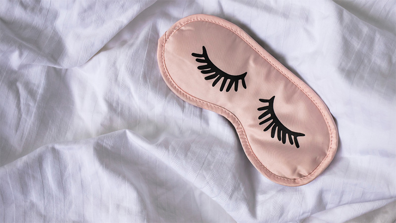An eye mask for sleeping on top of the sheets