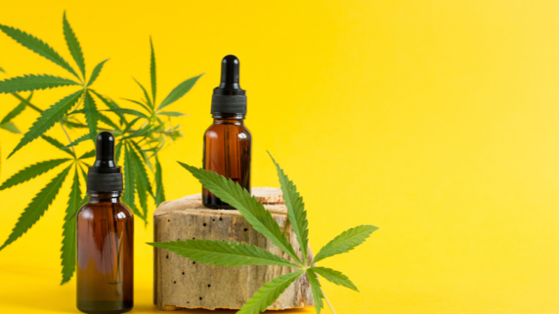 Bottles of CBD oil and Delta 8 tincture with hemp leaves on a yellow background