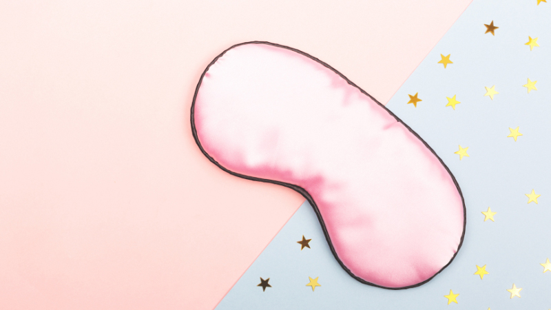 Sleeping mask and star confettis on light pink and blue background